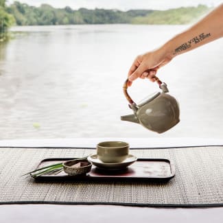 Tea poured from a pot with river in the background